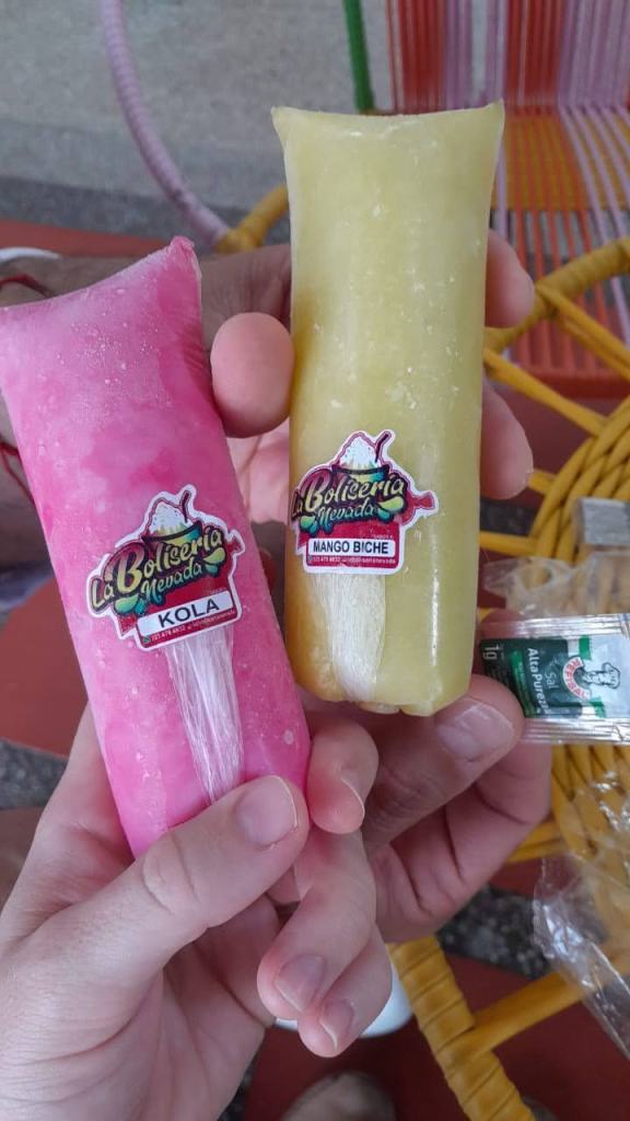 Two frozen bolis from La Boliseria Nevada in Santa Marta, Colombia. One is a pink Kola flavor, and the other is a yellow Mango Biche flavor. 